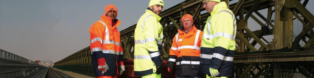 Beitragsbild zu Vizwell: Eine Gruppe von Männern in Warnschutzkleidung vor einer Brücke